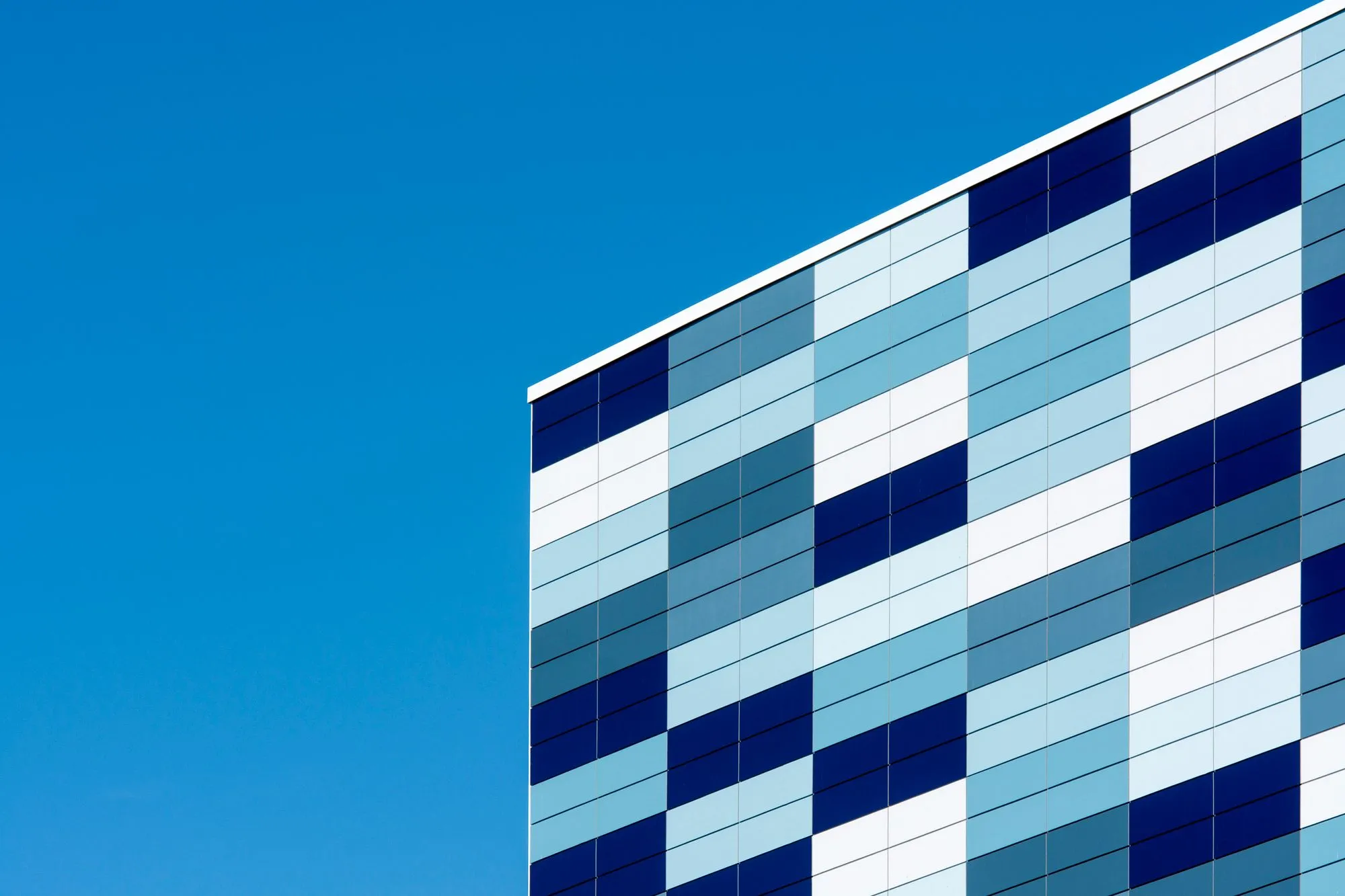Fachada de vidro azul em edifício moderno, representando a qualidade dos serviços de vidraçaria