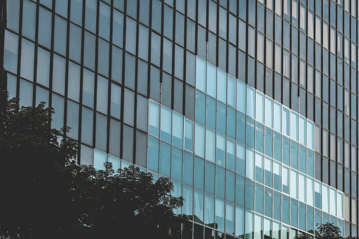 Fachada de vidro de edifício comercial refletindo o céu, representando a área de atuação da vidraçaria